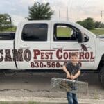 Child holding a rodent trap in front of a Camo Pest Control truck, emphasizing local pest removal services in New Braunfels, TX.